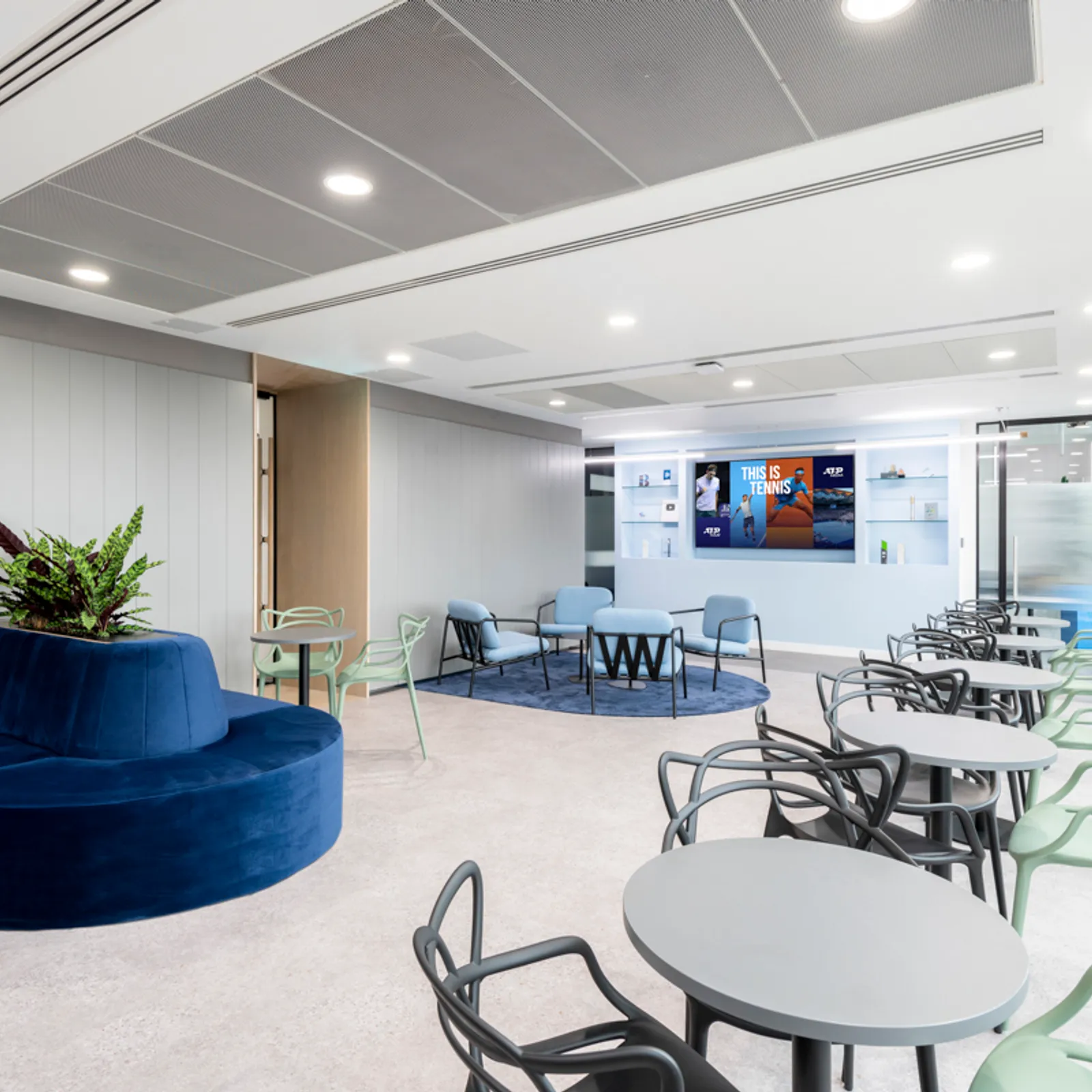 an office designed with chairs and tables in front of a large television screen